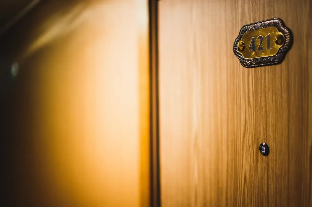 Warm toned image of a hotel room door with peephole in an orange hallway